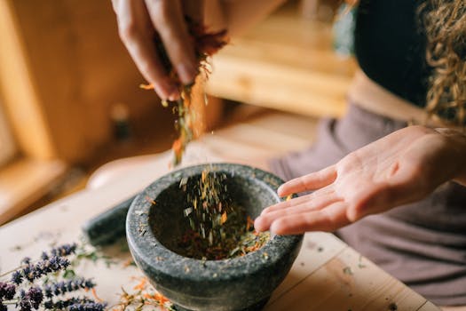 pexels-photo-5480253-5480253 A person preparing dried herbs using a mortar and pestle on a wooden table, seen from above.